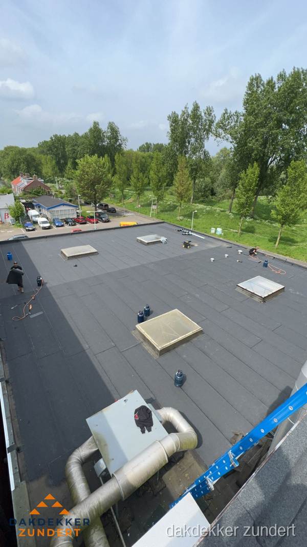 Dakdekker aan het werk op groot plat dak met bitumen in Zundert Dakdekker aan het werk op groot plat dak met bitumen in Zundert